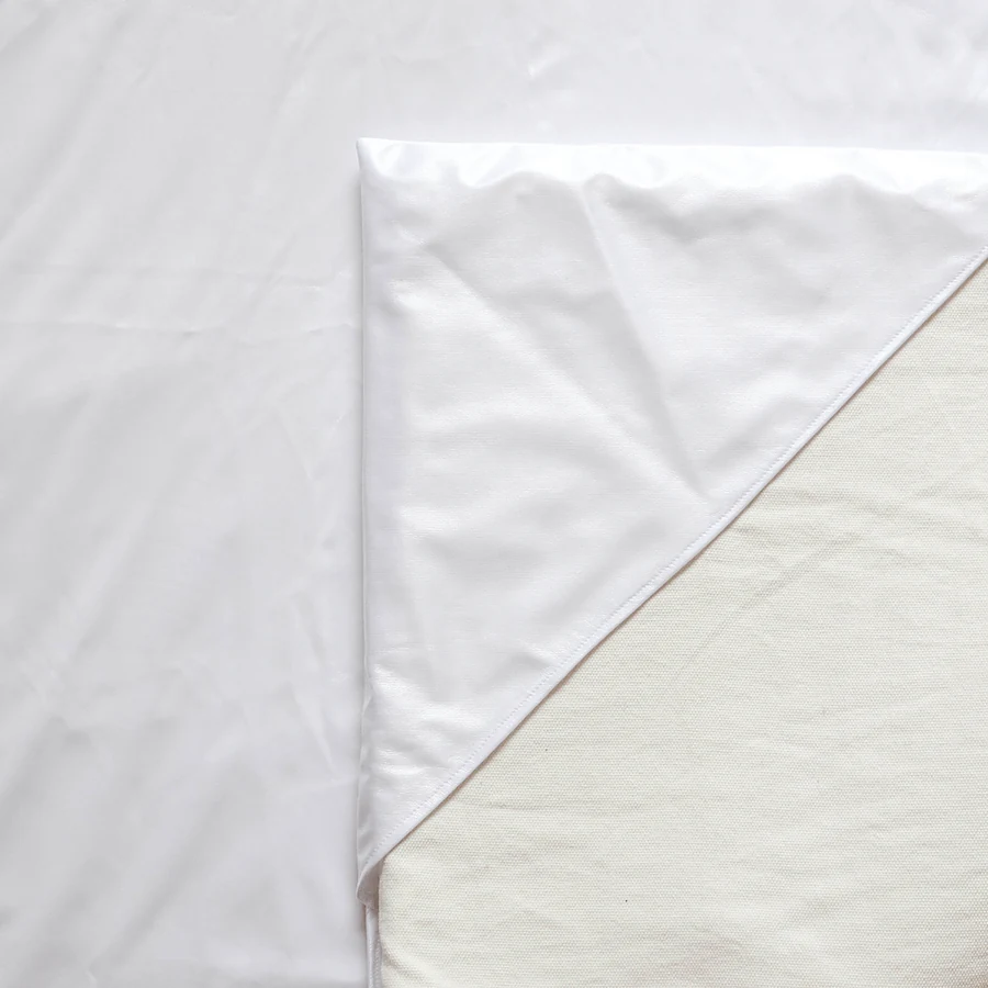 L'alèse en coton écru qui entoure la mousse du Tapis Magique, sous la housse imprimée