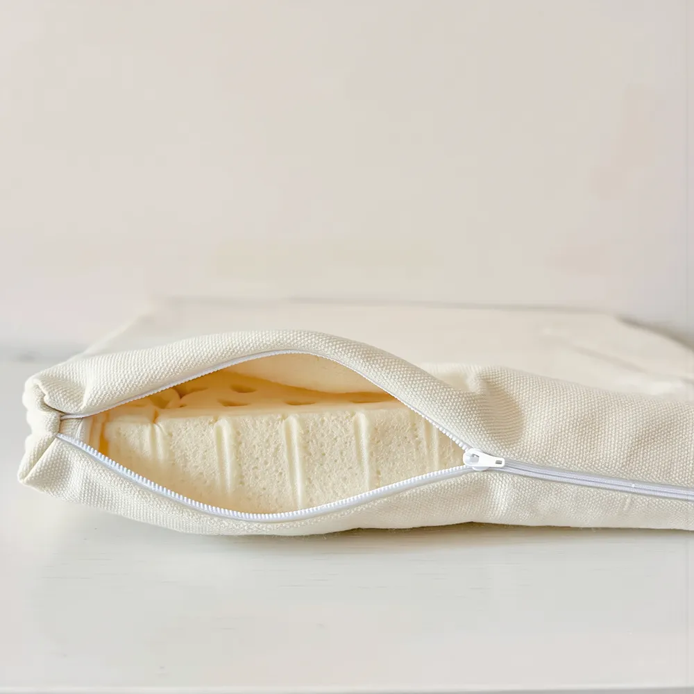 L’alèse zippée à moitié ouverte, la mousse en latex visible à l’intérieur.