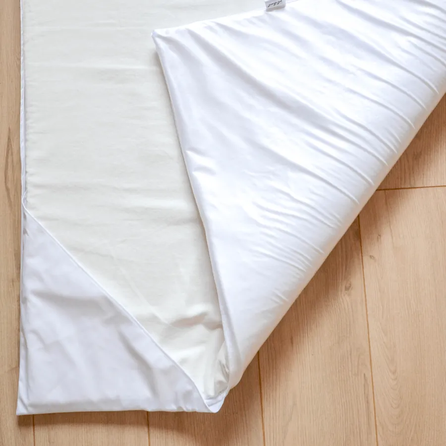 Insert imperméable blanc à moitié roulé sur un parquet clair, envers et endroit visibles