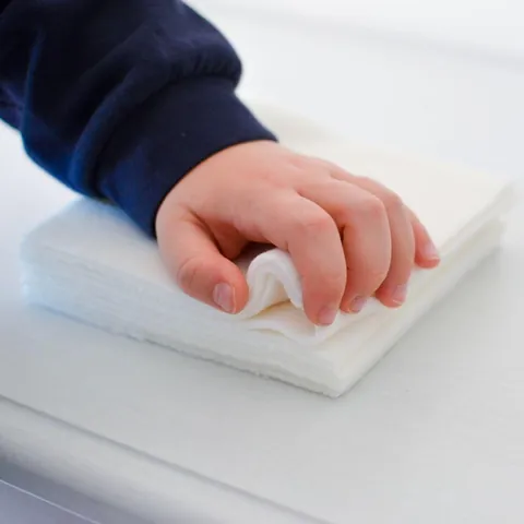Main d'enfant posée sur une pile de lingettes lavables blanches
