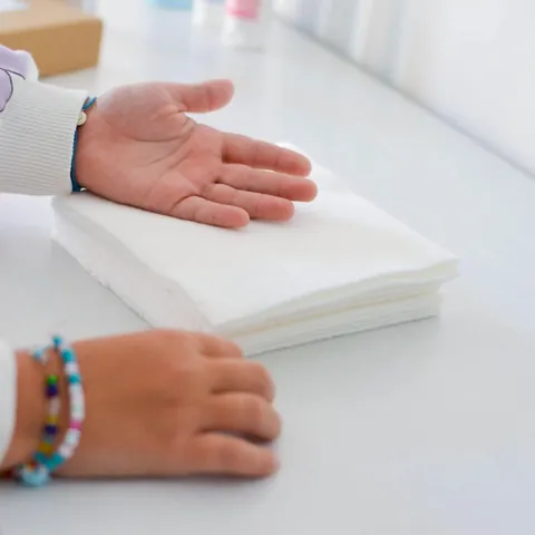 Mains d'enfant près d'une pile de lingettes lavables, bracelet de perles