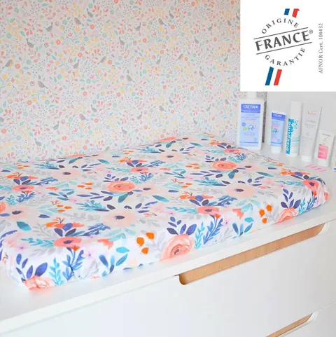 Matelas à langer Bouquet sur la commode, produits de soin et papier peint fleuri, logo Origine France Garantie