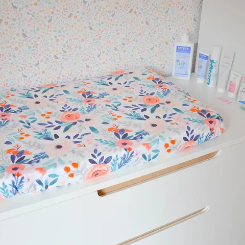 Matelas à langer Bouquet sur la commode, flacons de soin et papier peint fleuri
