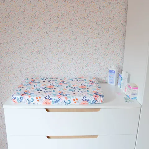 Matelas à langer Bouquet sur la commode blanche, produits de soin, cadrage plus serré
