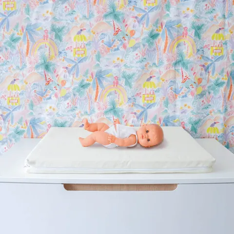 Poupon sur le matelas à langer en housse écrue, tissu Jungle tendu en fond