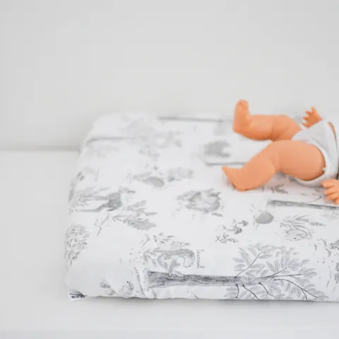 Matelas à langer Doux sous-bois vu de biais, jambes du poupon