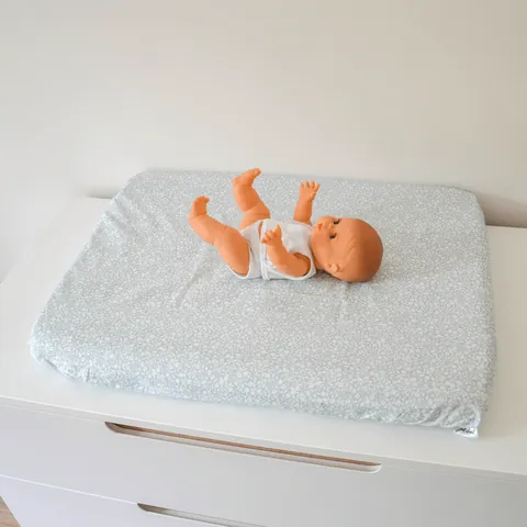 Poupon sur le matelas à langer Gabi vu de biais, commode blanche