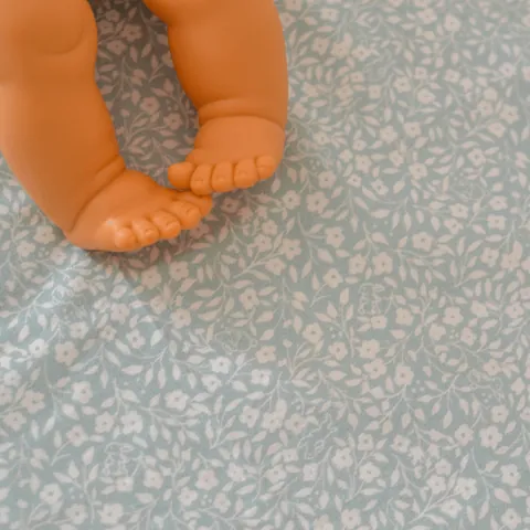 Gros plan sur le tissu Gabi à petites fleurs blanches, pieds du poupon