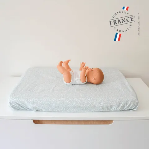 Poupon allongé sur le matelas à langer Gabi vert d'eau, logo Origine France Garantie