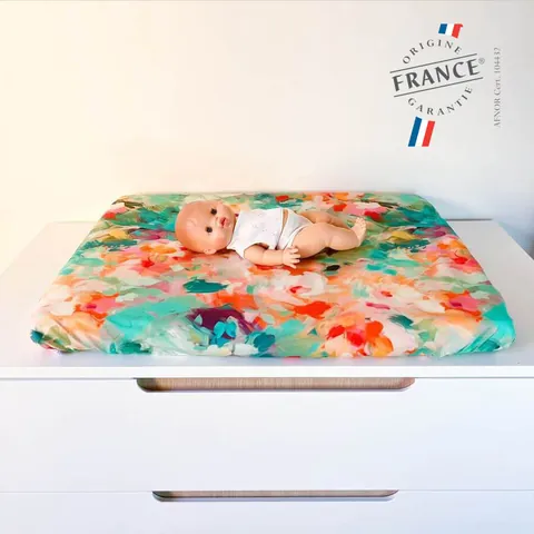 Poupon sur le matelas à langer Jardin aux fleurs peintes, logo Origine France Garantie