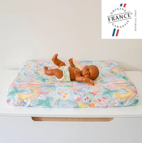 Poupon allongé sur le matelas à langer Jungle pastel posé sur une commode blanche, logo Origine France Garantie