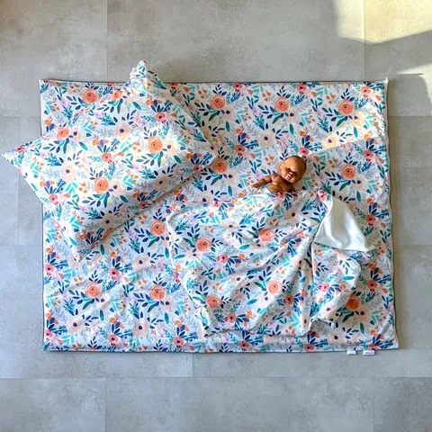 Poupon sur le tapis bouquet avec l'oreiller et la couverture assortis, vue de dessus