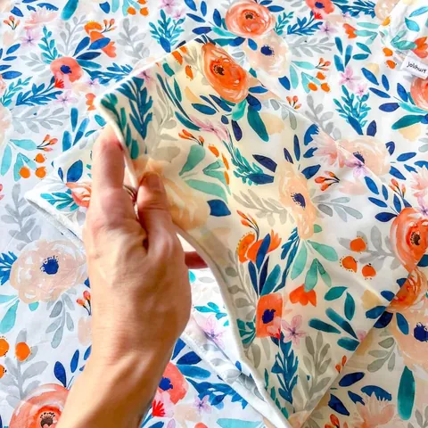 Main qui soulève un coin de la couverture bouquet pour montrer l'imprimé, gros plan