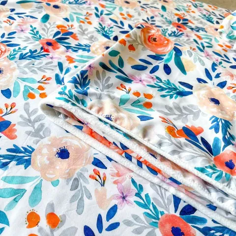 Couverture bouquet pliée, bord de la doublure visible, posée sur le tapis assorti