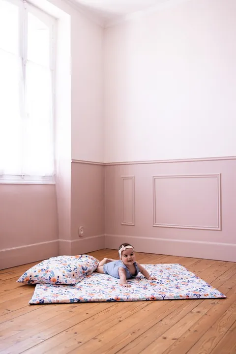 Bébé sur le ventre sur le tapis Bouquet, oreiller Bouquet en tête de tapis, plan large de la chambre