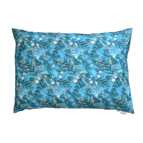 Oreiller housse bleu canard à feuillages et fleurs blanches, posé à plat sur fond blanc