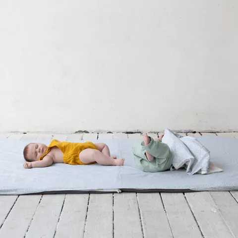 Deux bébés allongés sur la surhousse géante vert de gris, plancher blanc