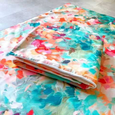 Couverture jardin aux touches de peinture vives pliée, posée sur le tapis assorti