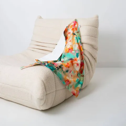 Couverture jardin drapée sur un fauteuil bas en bouclette écrue