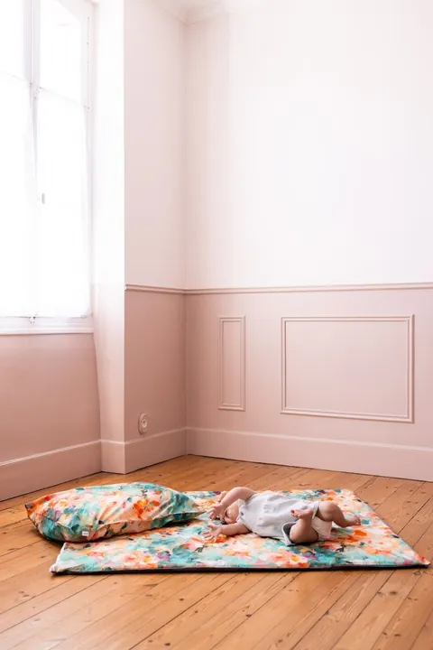 Bébé allongé sur le tapis Jardin, oreiller Jardin en tête de tapis, plan large de la chambre rose
