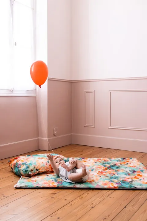Bébé allongé la tête sur l'oreiller Jardin qui attrape la ficelle d'un ballon orange