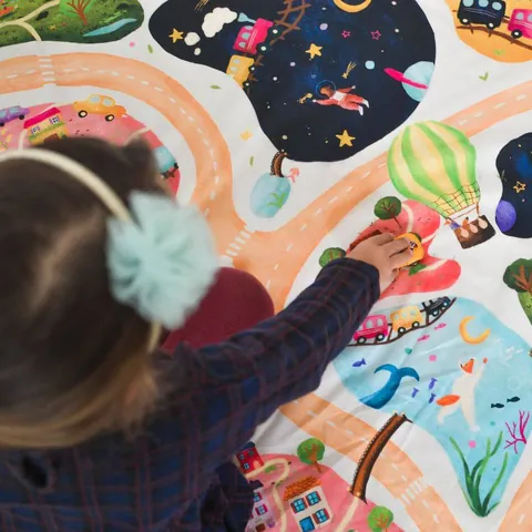 Petite fille qui montre une montgolfière sur l'imprimé Croisée des mondes, vue de dos