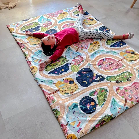 Petite fille bras en croix sur la sur-housse géante À la croisée des mondes, vue de biais