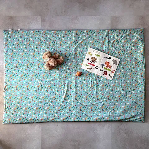 Surhousse géante vert d'eau à fruits étalée au sol, ours en peluche et imagier, vue de dessus