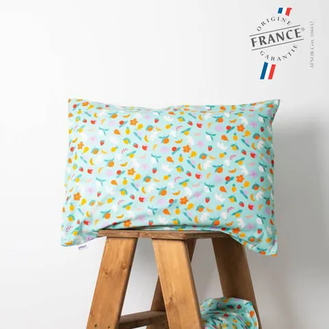 Oreiller housse vert d'eau à fruits posé sur un tabouret en bois, logo Origine France Garantie