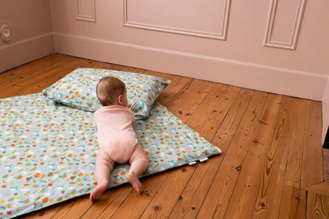 Bébé à quatre pattes vers l'oreiller Pique-nique posé en haut du tapis, parquet et murs roses