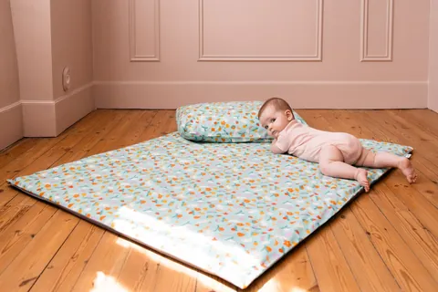 Bébé allongé contre l'oreiller Pique-nique, plan large du tapis sur le parquet