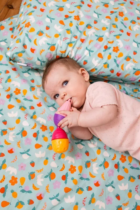 Bébé qui mâchouille un jouet, la tête sur l'oreiller Pique-nique, gros plan vertical