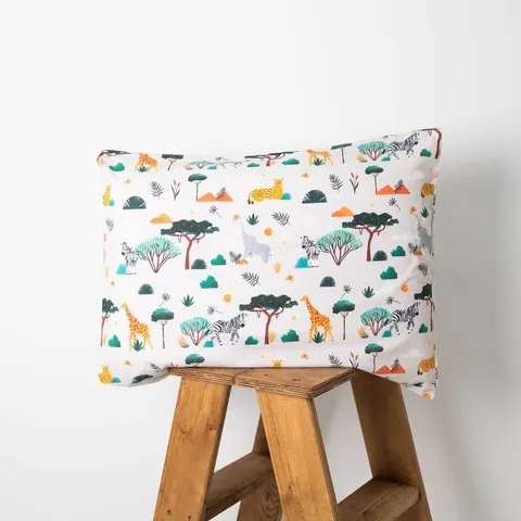 Oreiller housse savane posé sur un tabouret en bois, fond blanc