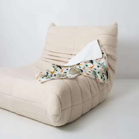 Couverture savane drapée sur un fauteuil bas en bouclette écrue