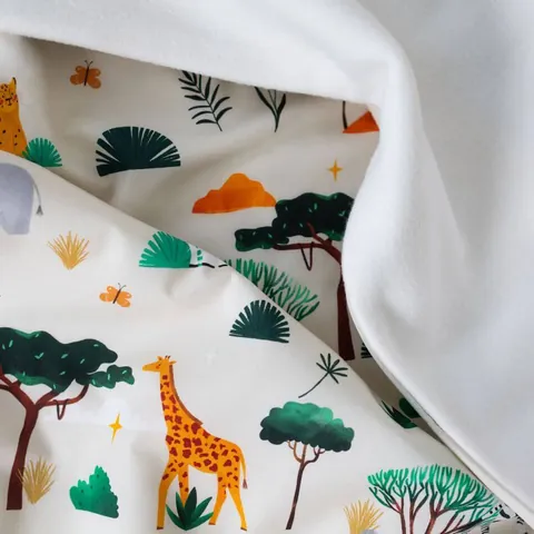 Couverture savane soulevée sur sa doublure blanche, girafe et acacias, gros plan