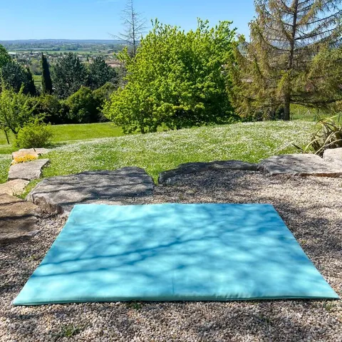 Le Tapis Magique Le baroudeur posé seul sur le gravier d'un jardin, face à la vallée