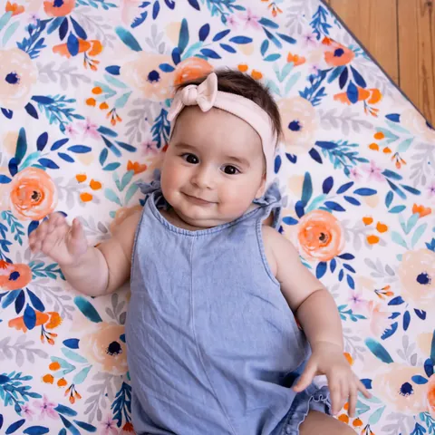 Bébé souriant sur le dos sur l'imprimé Bouquet, cadrage serré vue du dessus