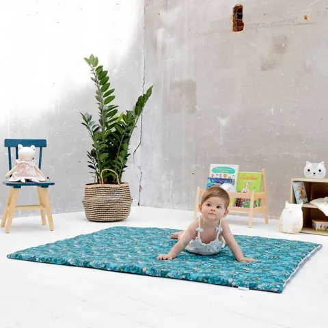Bébé sur le ventre sur le tapis vert d'eau à feuillages, plan large