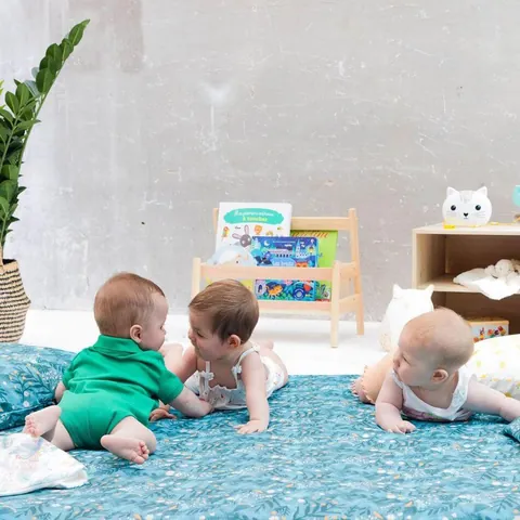Trois bébés allongés et assis sur le Tapis Magique Forêt magique