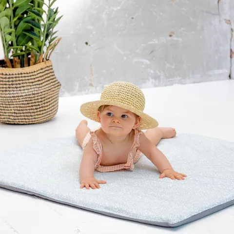 Petite fille au chapeau de paille allongée sur le tapis Gabi, face à l'objectif