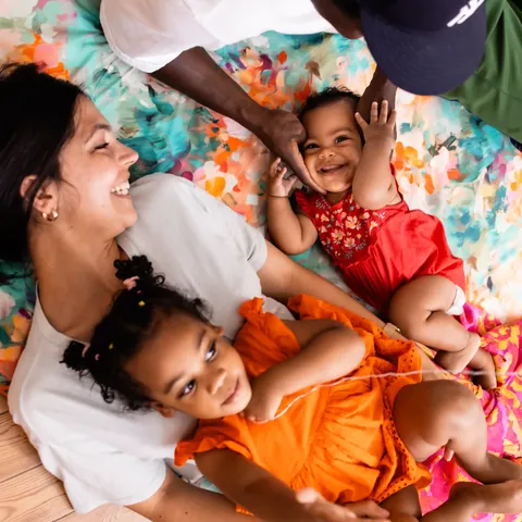 Famille allongée sur le tapis Jardin vue du dessus : mère, père, fillette et bébé qui rit