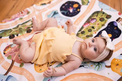 Bébé en barboteuse jaune allongé sur le tapis Croisée des mondes, regard vers l'objectif, plan rapproché