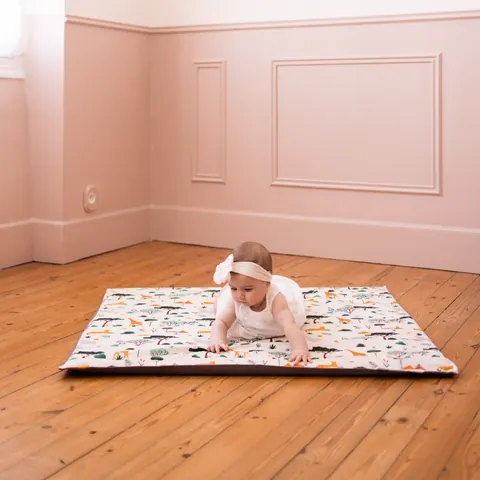 Bébé à quatre pattes sur le tapis Croisée des mondes posé sur un parquet, chambre rose moulurée, plan large, tapis entier