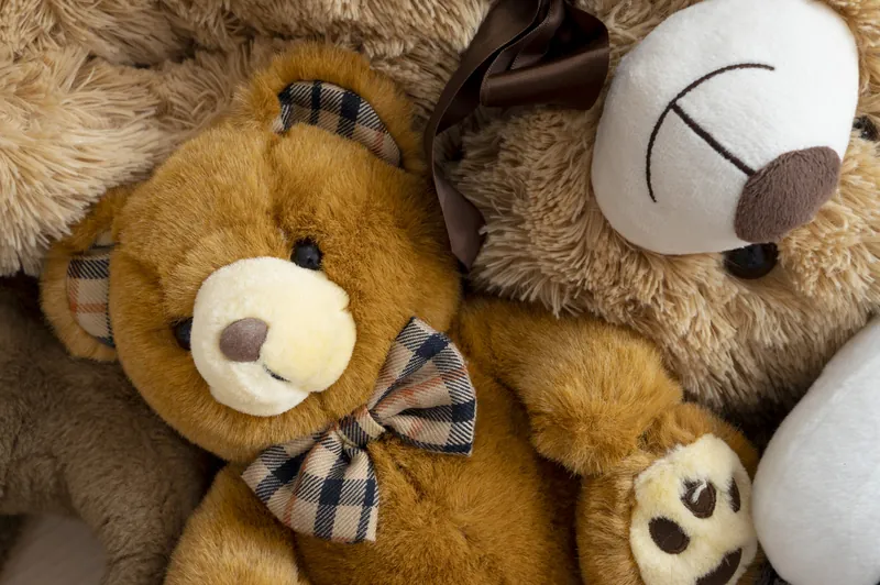 Des ours en peluche entassés, dont un ourson brun à nœud papillon écossais