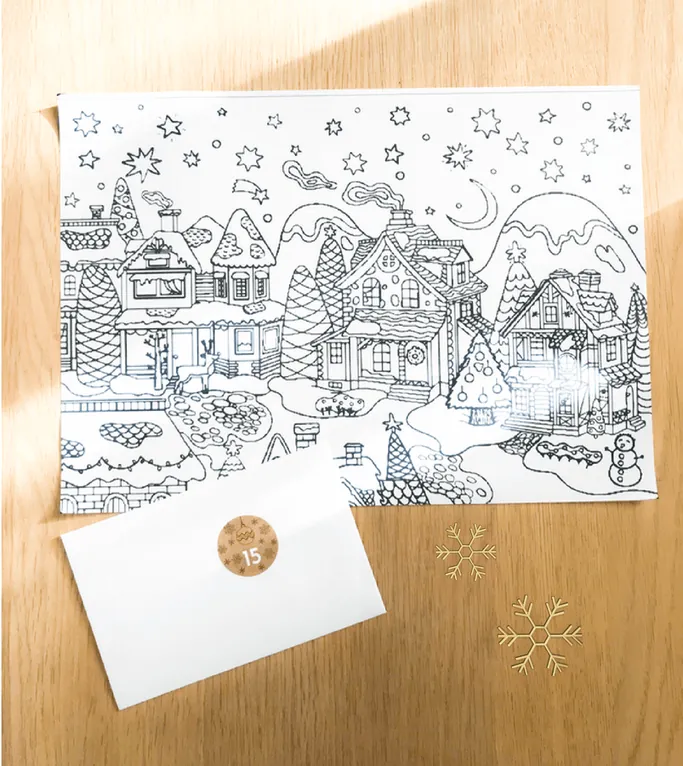 Un coloriage de village enneigé imprimé, au-dessus d'une enveloppe blanche marquée d'une gommette 15