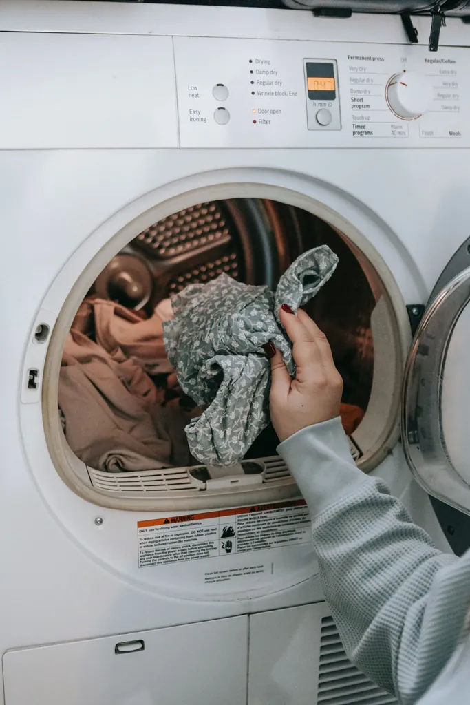Une main qui sort du linge imprimé du tambour d'un lave-linge à hublot