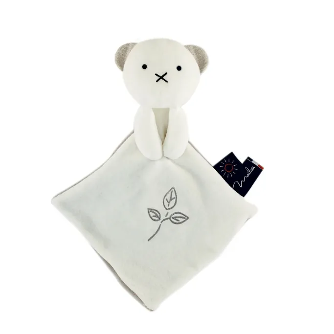 Un doudou plat blanc à tête d'ours, brodé d'une feuille, sur fond blanc