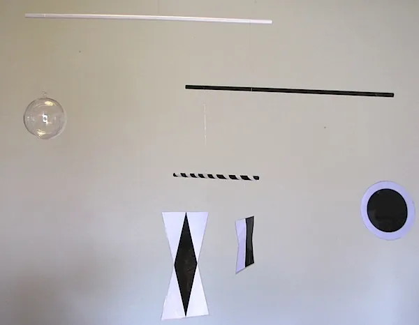 Le mobile de Munari : des formes géométriques noires et blanches et une sphère transparente suspendues à des baguettes