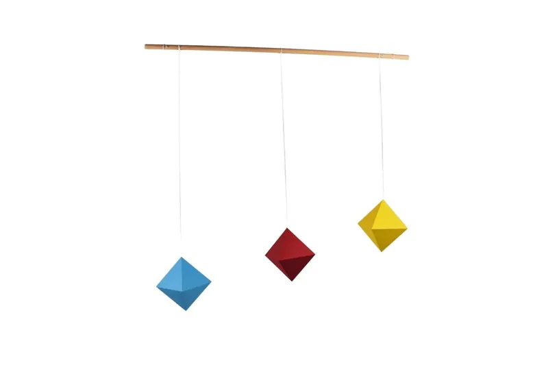 Le mobile des octaèdres : trois octaèdres en papier bleu, rouge et jaune suspendus à une baguette en bois