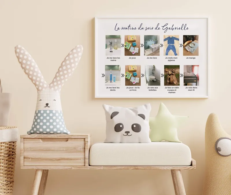 Tableau « La routine du soir de Gabrielle » accroché au mur au-dessus d'un banc en bois garni de coussins lapin, panda et étoile